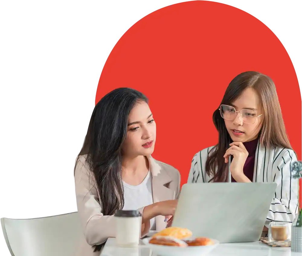Two women collaborating with laptop and pastries